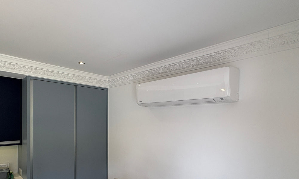 Bedroom air conditioning unit installed neatly above a bed